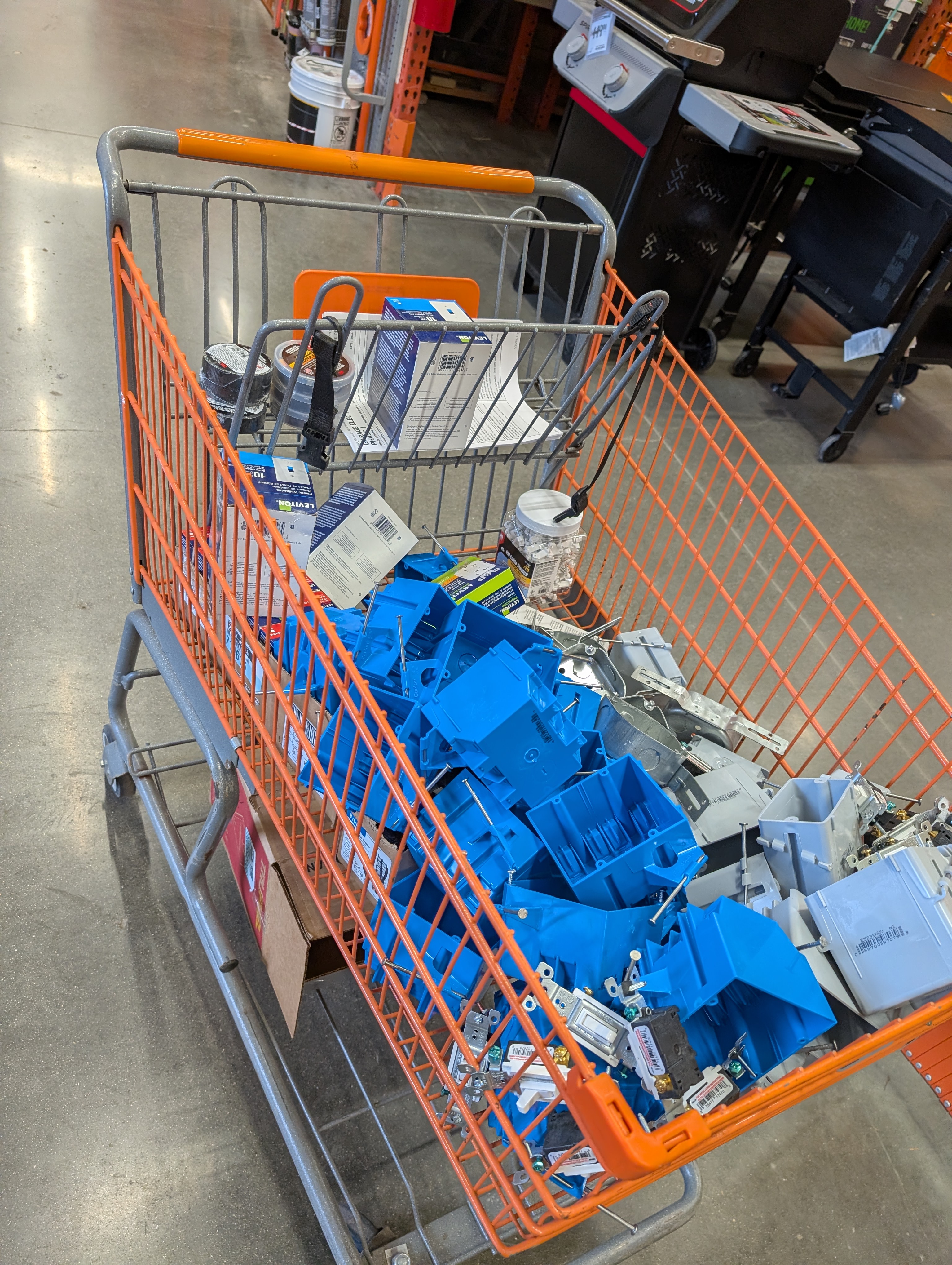 Loaded HD orange flatbed cart at register with blue plastic boxes, breakers, GFCIs, and tools