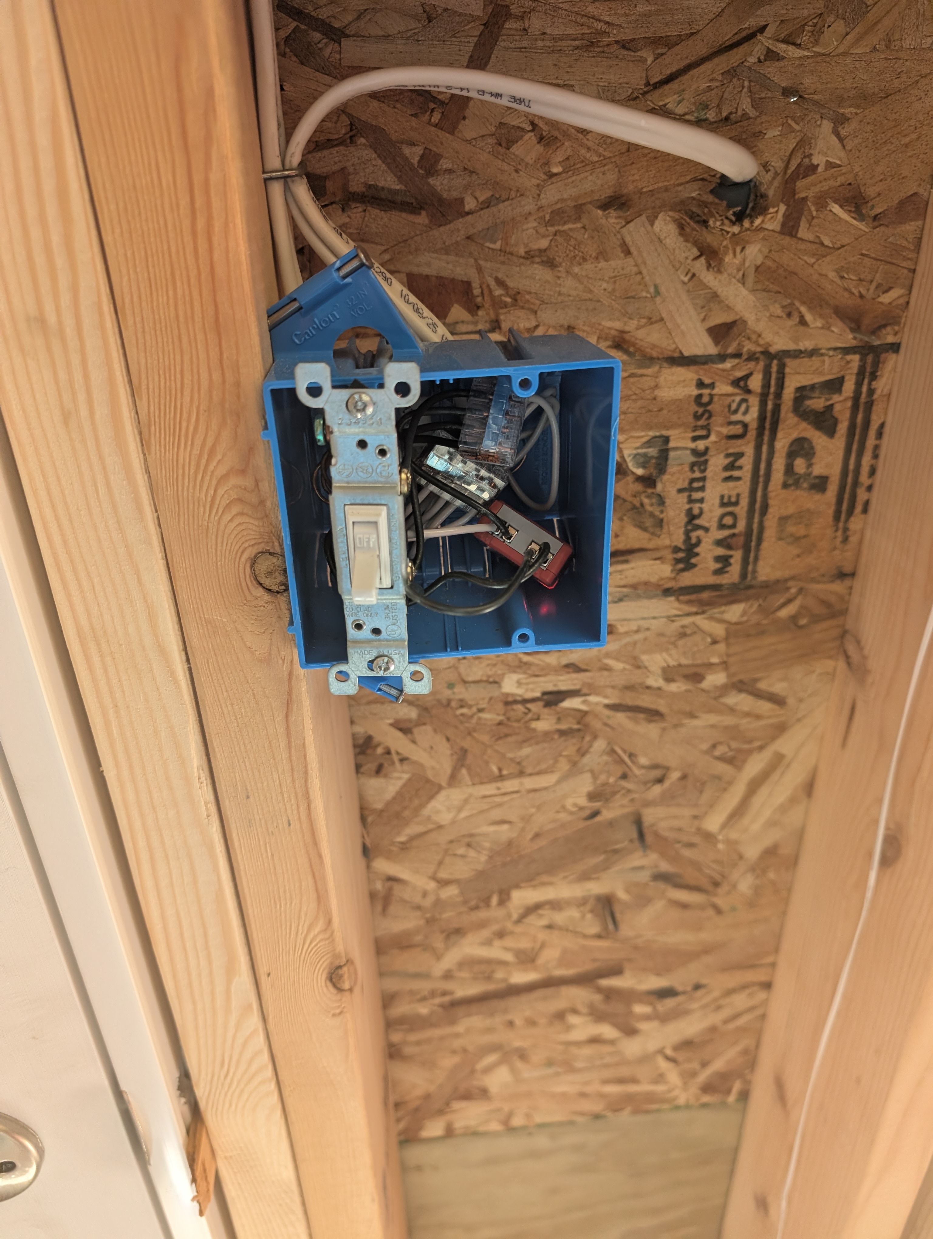 Existing exterior-light switch box at the service door, left gang switched, right gang open for the future interior 3-way