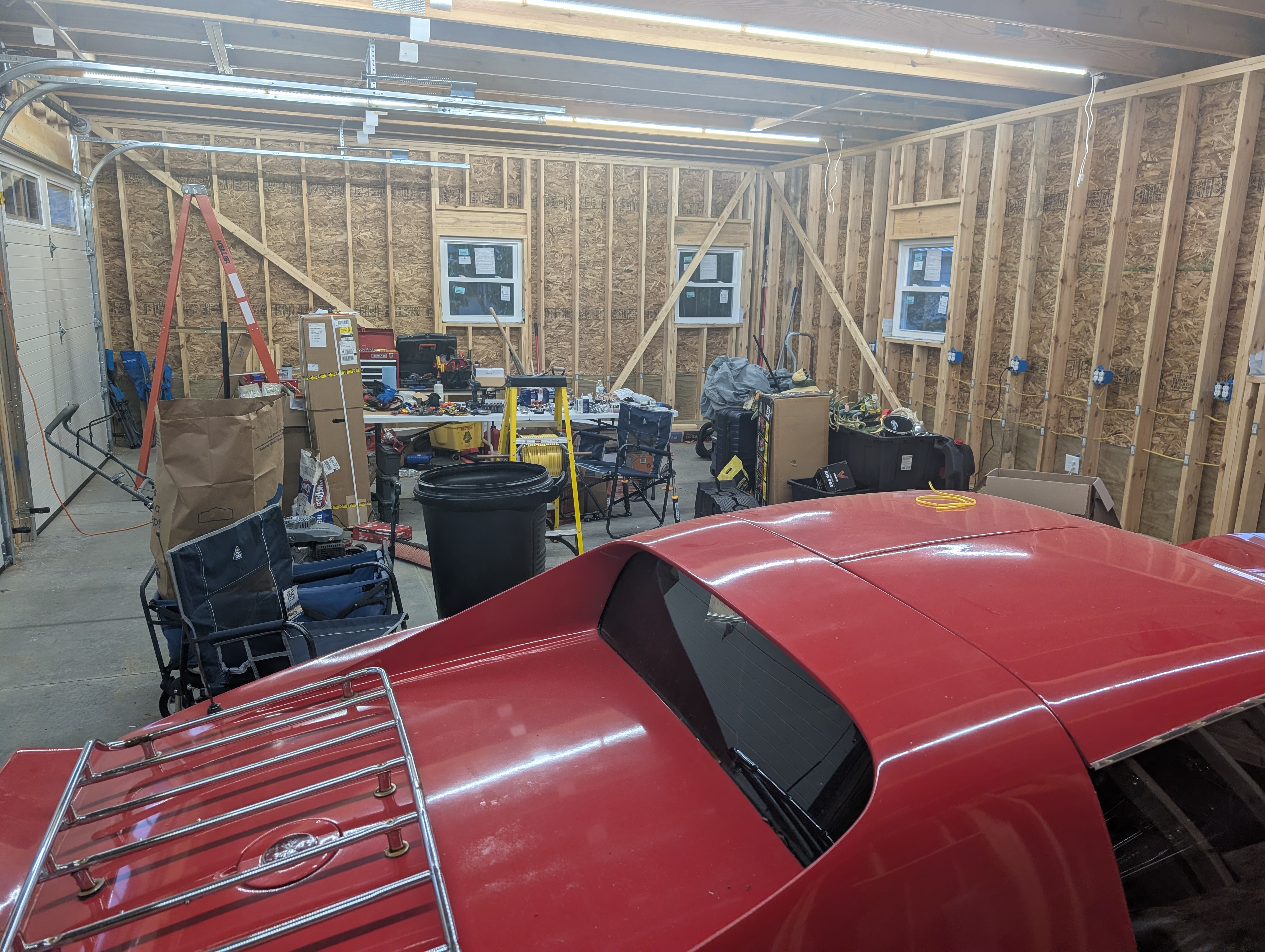Floor-level view of the brightly-lit garage at night with the red Corvette parked in the bay under the new LED lighting