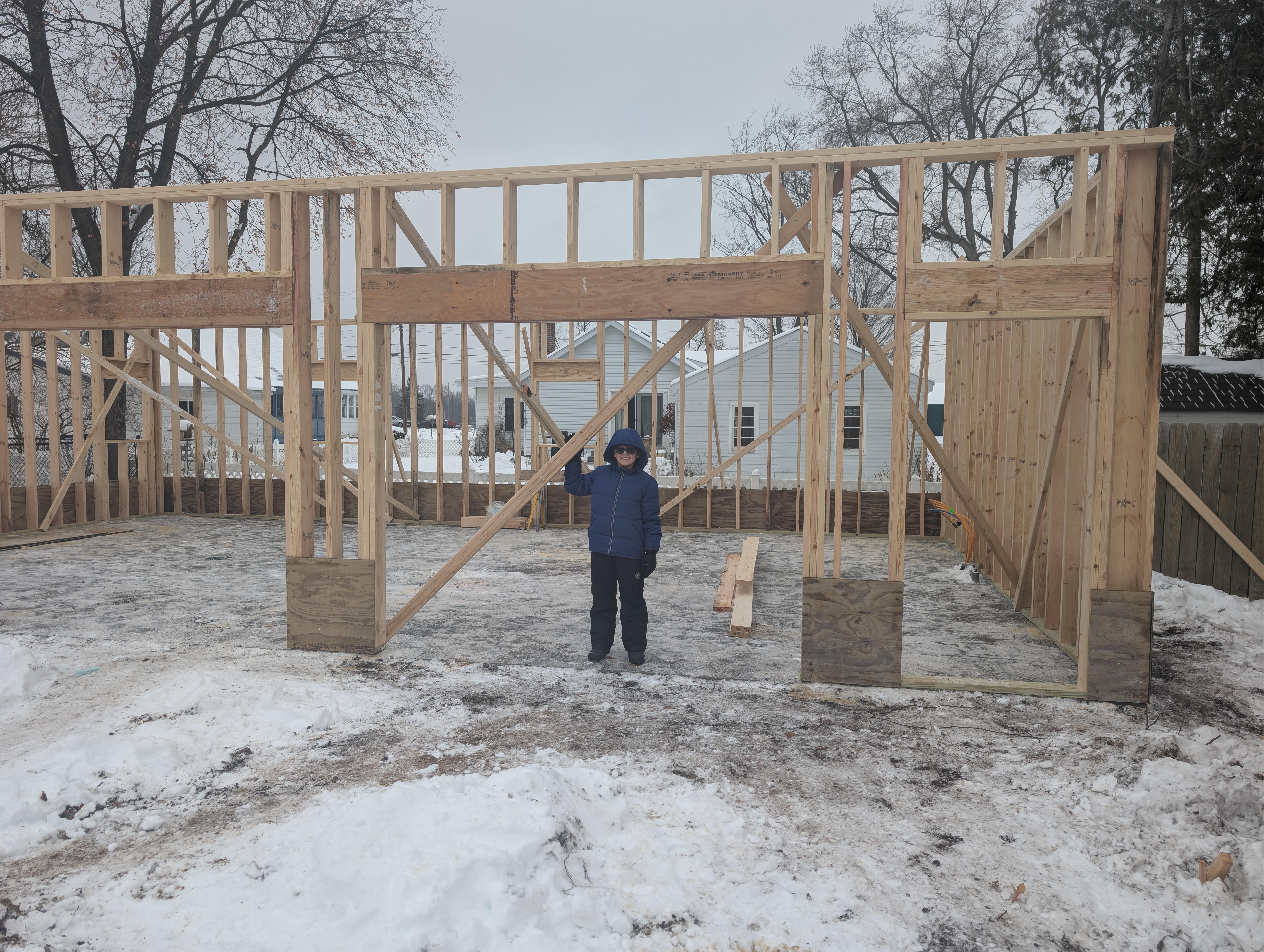 Front view of framed garage with center bay bracing and person for scale