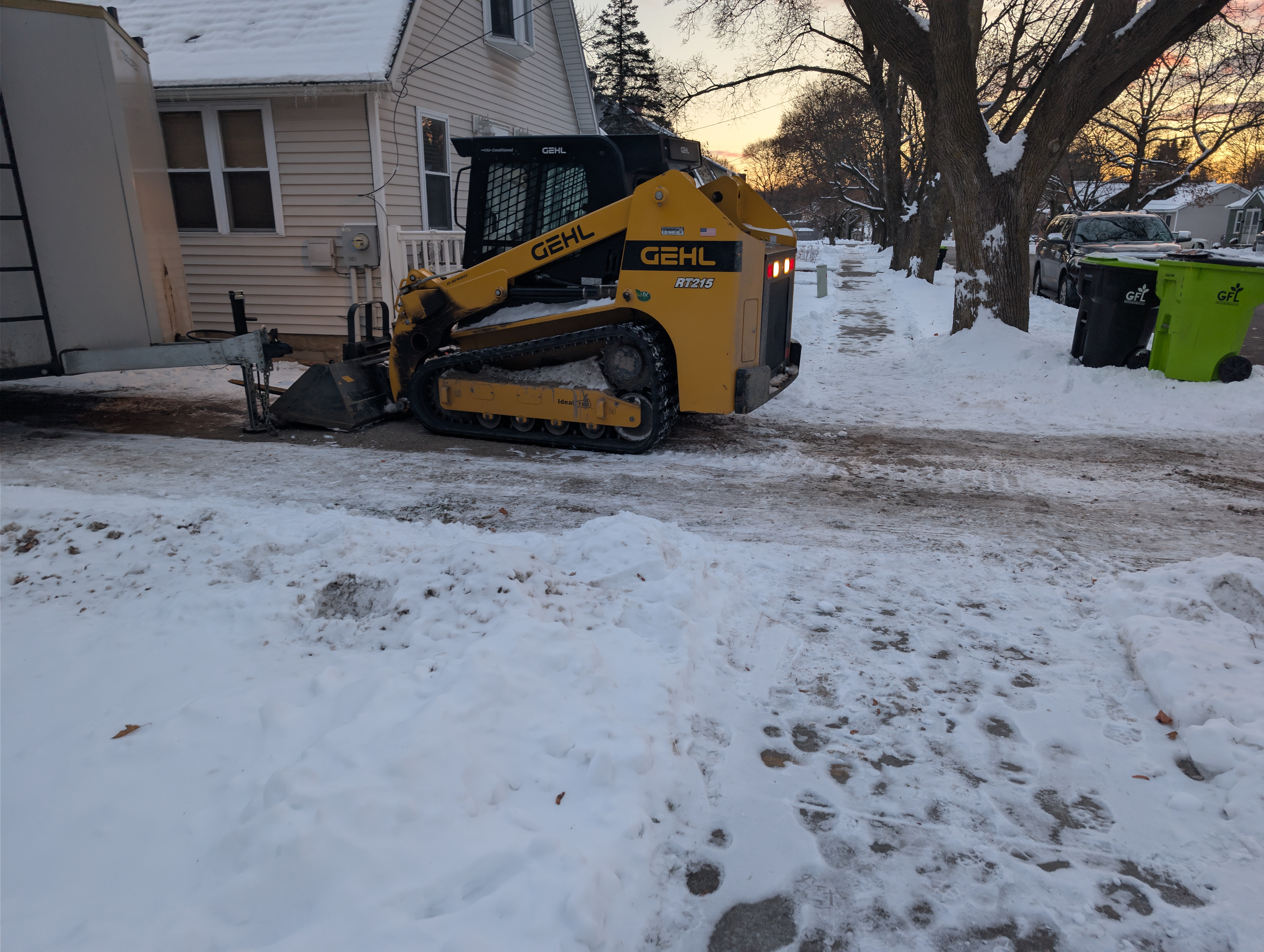 Gehl RT215 track loader unloading beside house