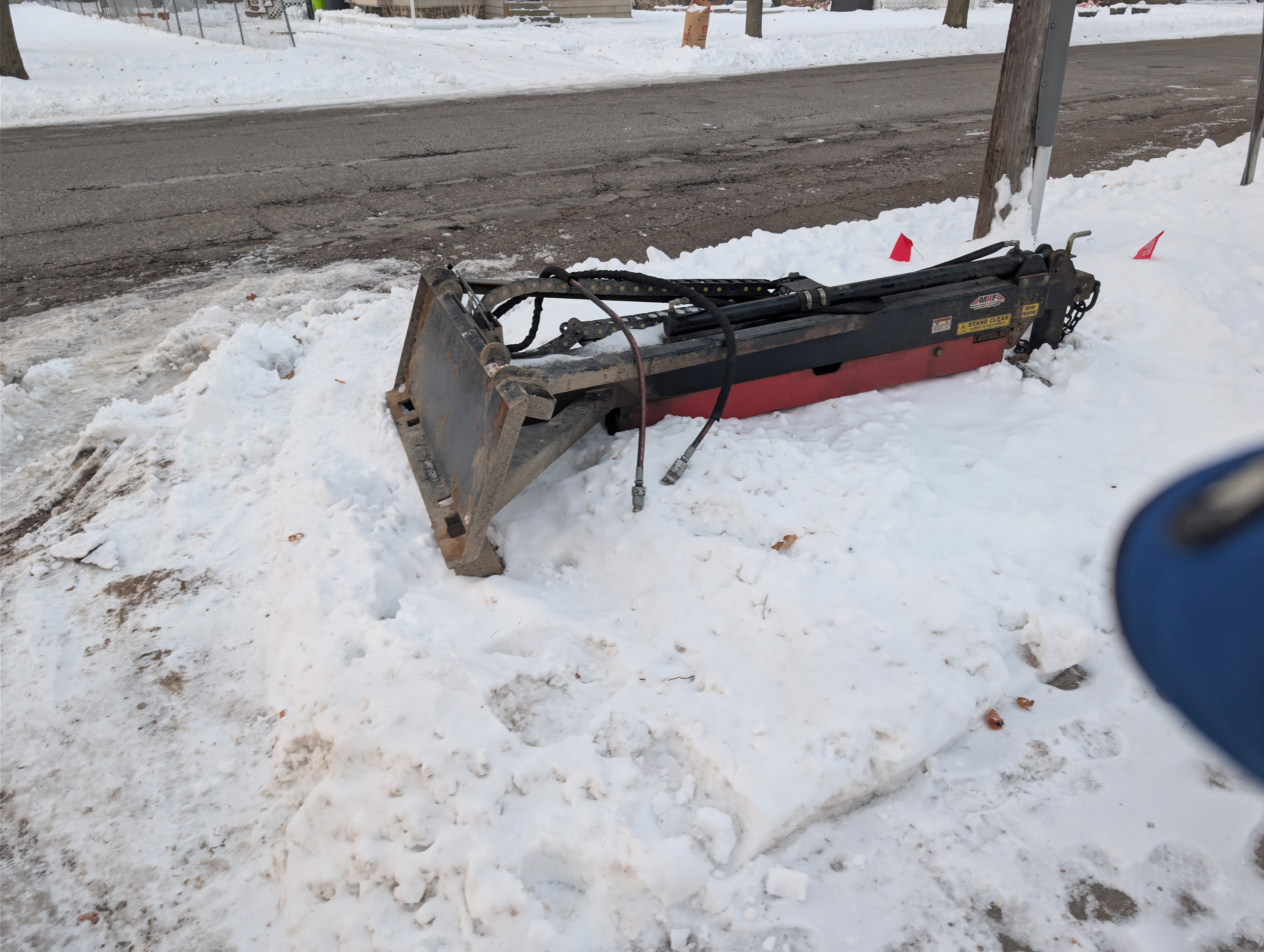 Hydraulic auger attachment staged near curb