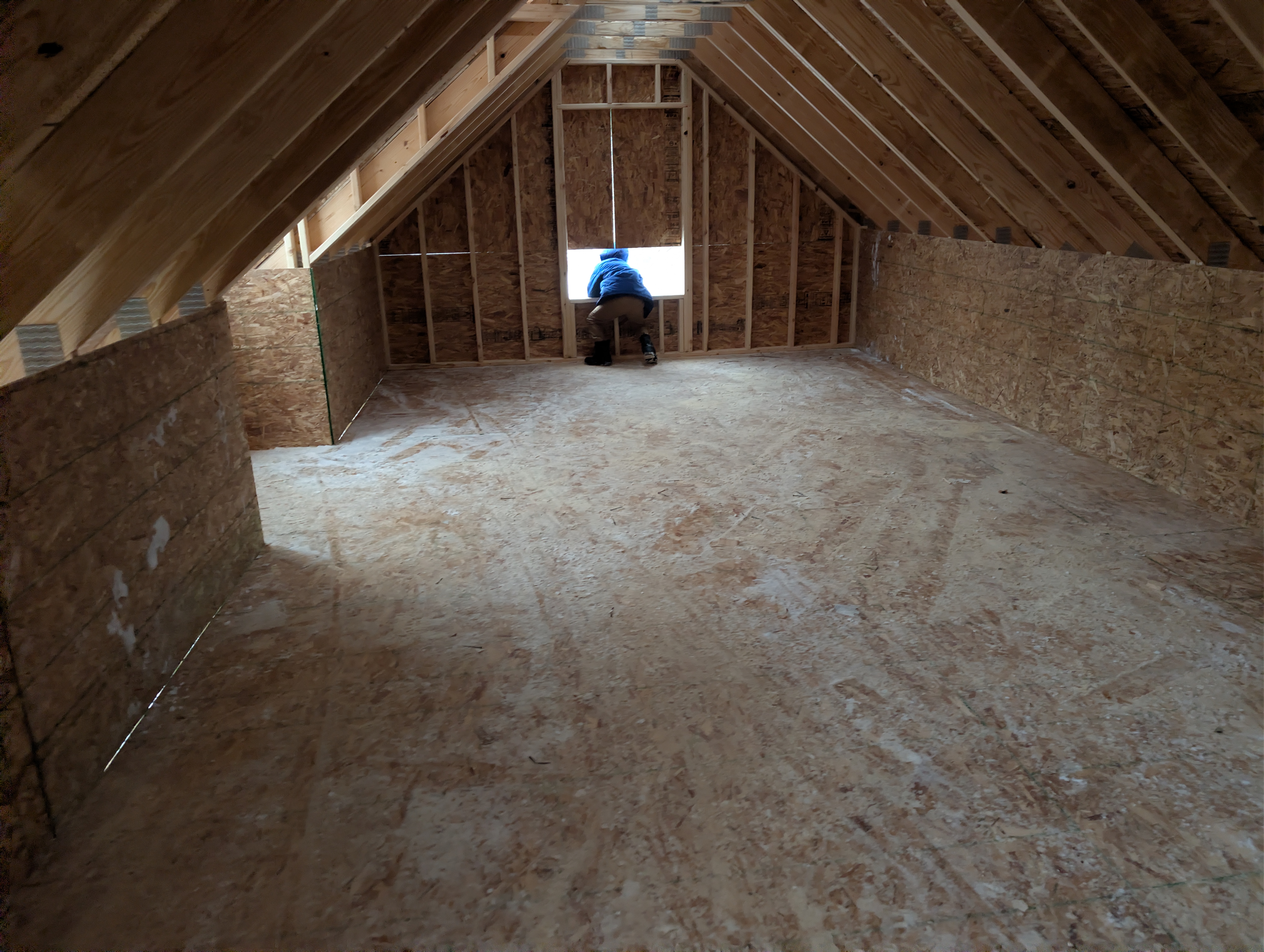 Child leaning out framed dormer opening from loft