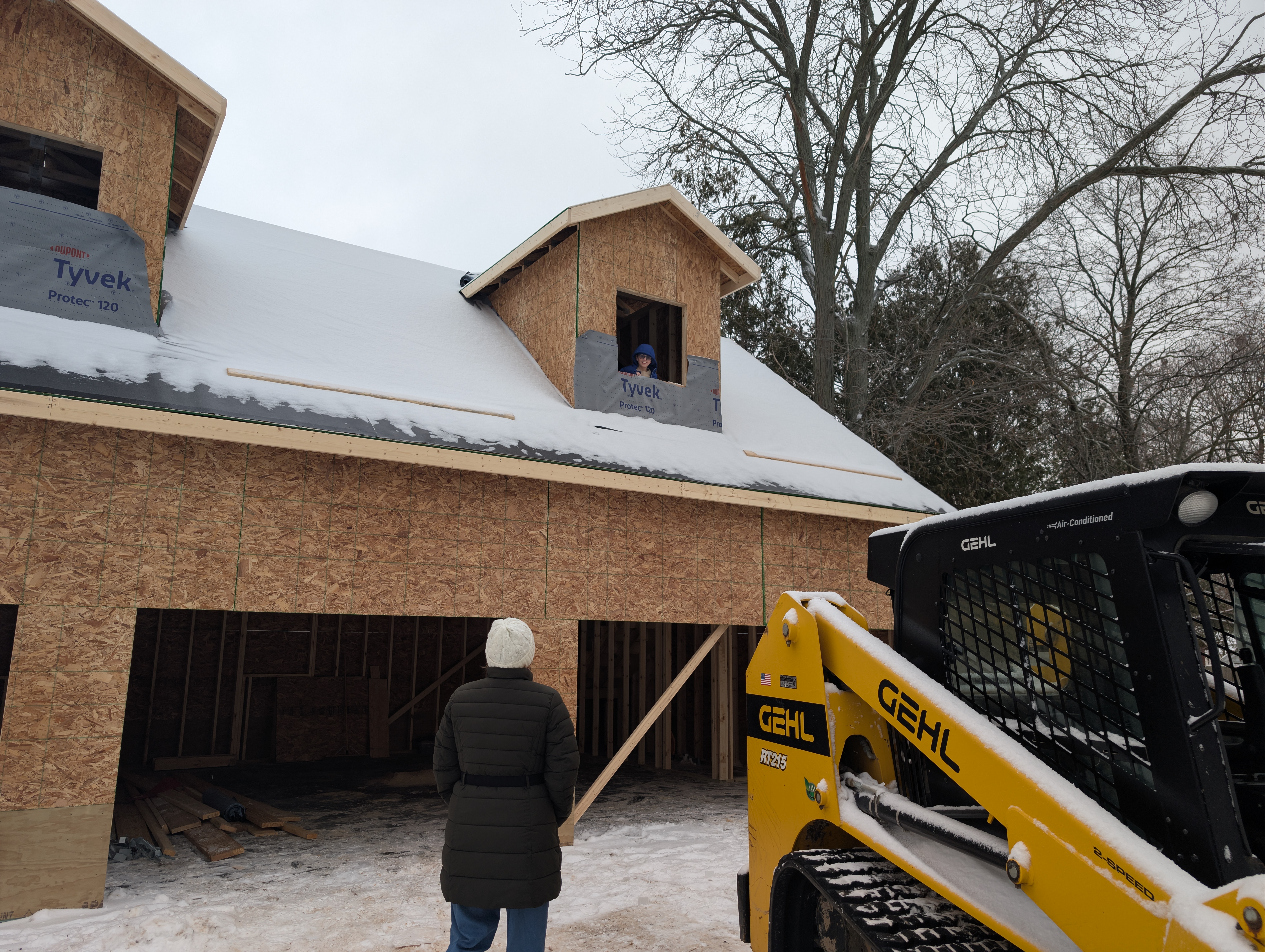 Person looking up at child in dormer opening, exterior view
