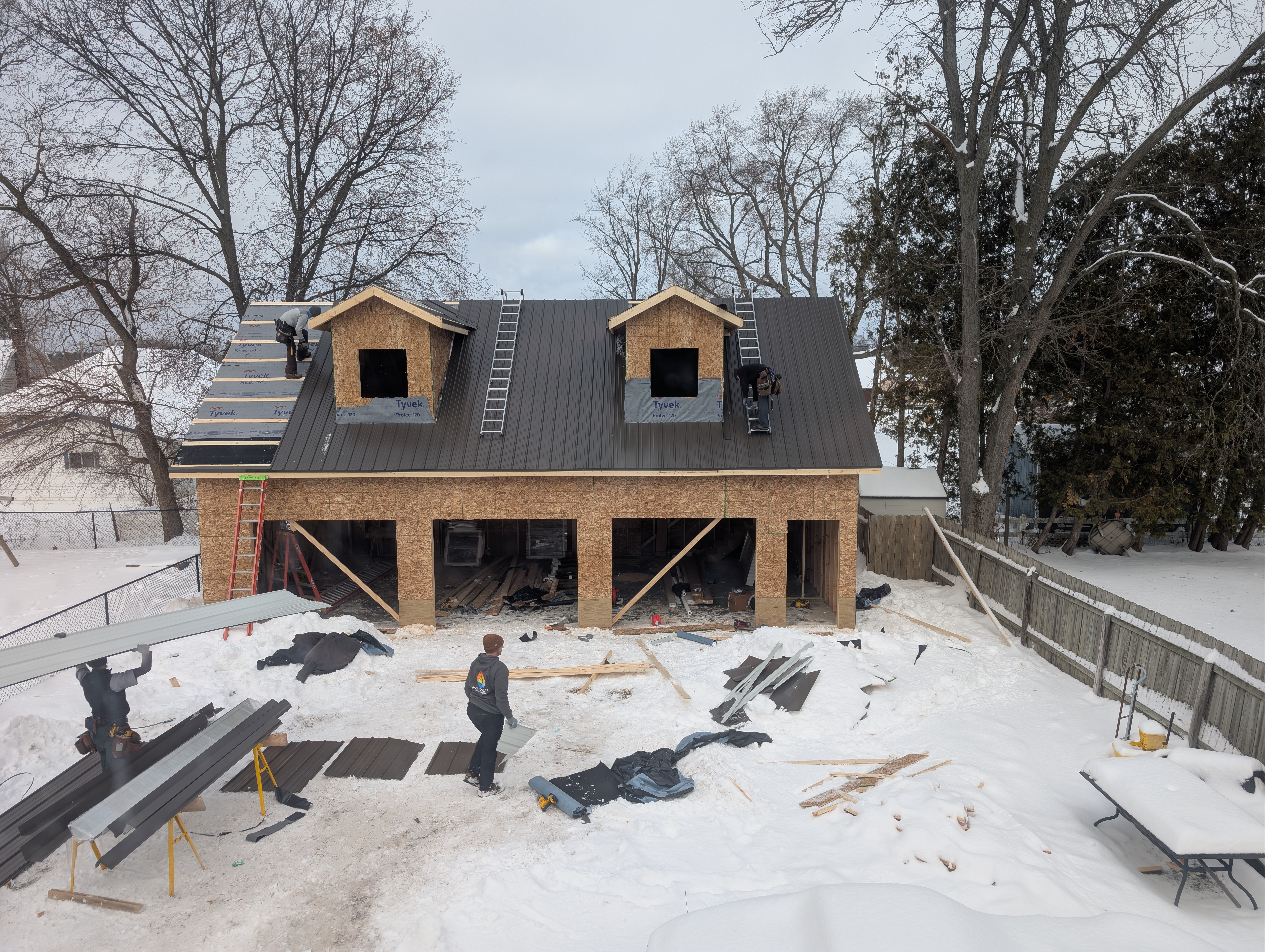 Crew installing standing-seam roof panels on dormers