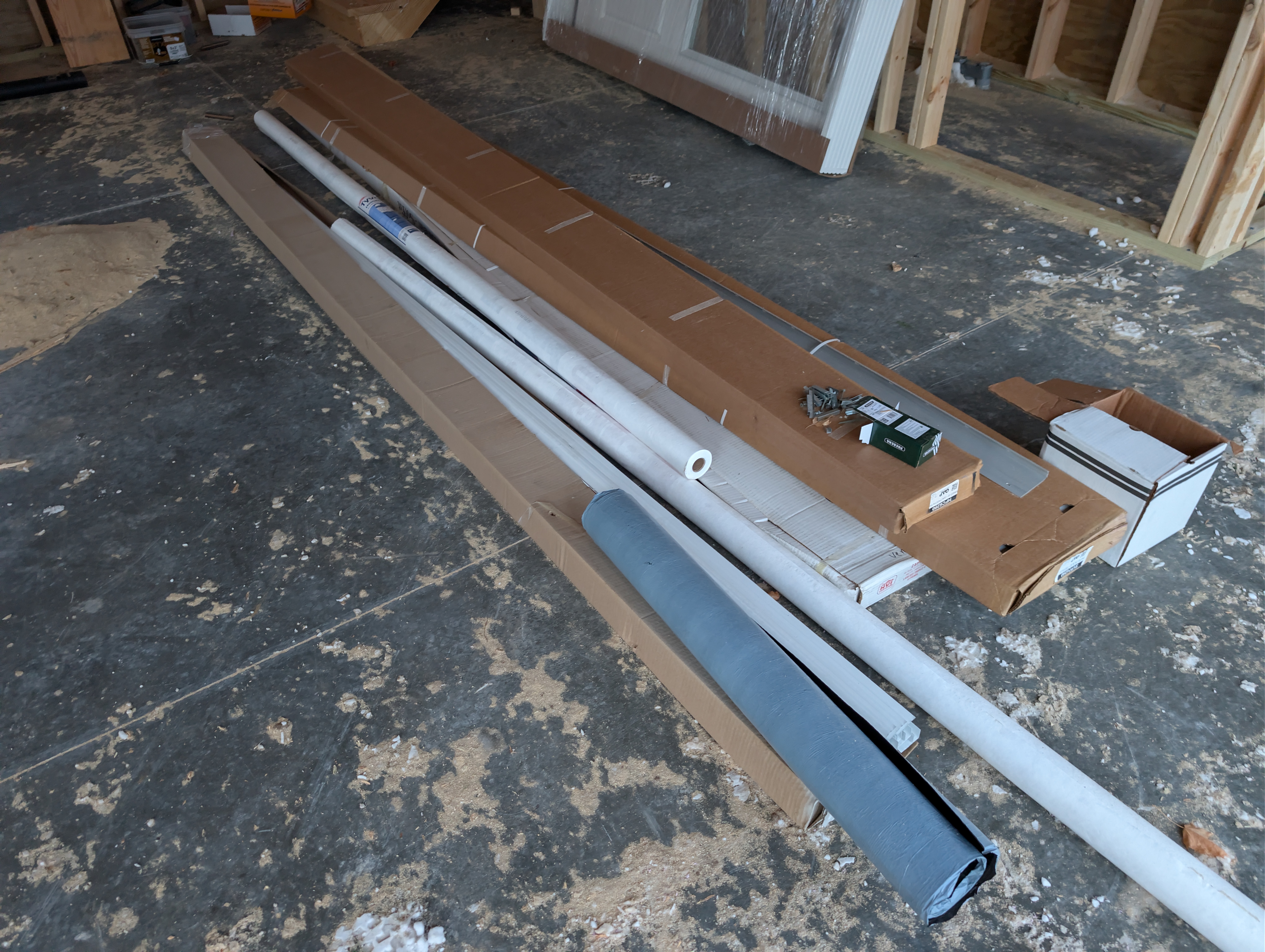 Housewrap, trim, and fasteners laid out on floor