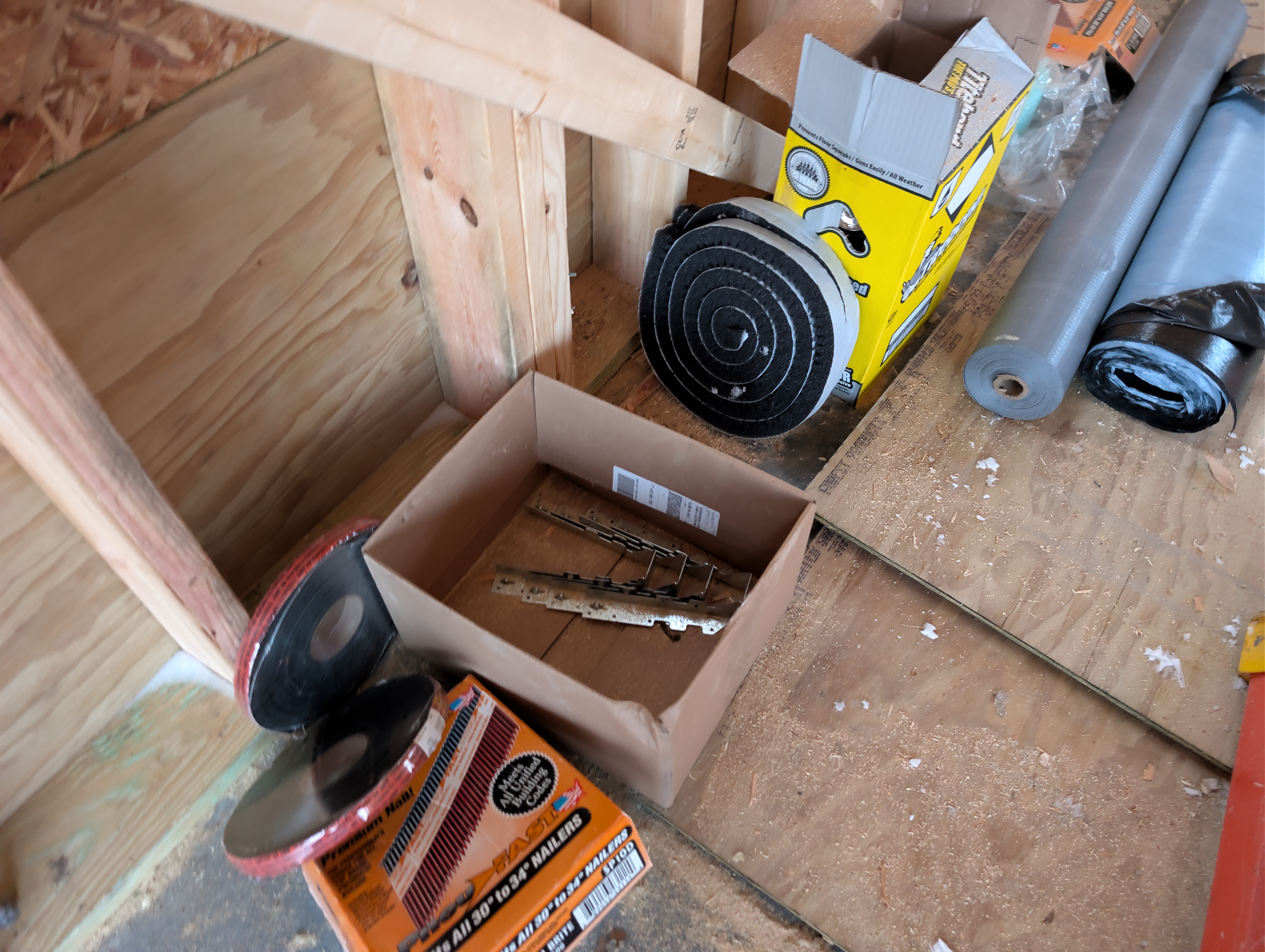 Roofing foam closures, nails, and hardware staged on floor