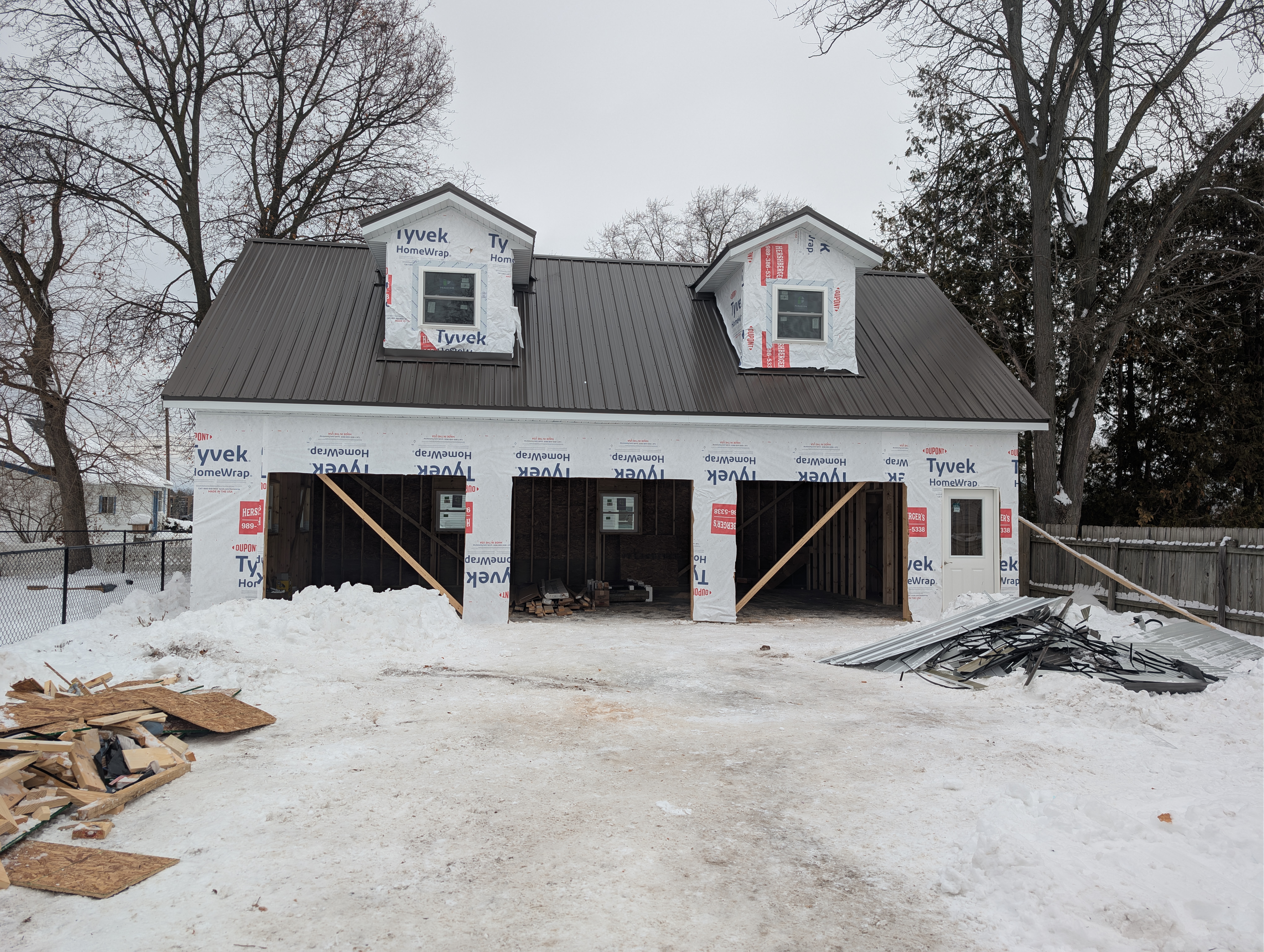 Straight-on front view showing Tyvek wrap, finished roof, and installed windows
