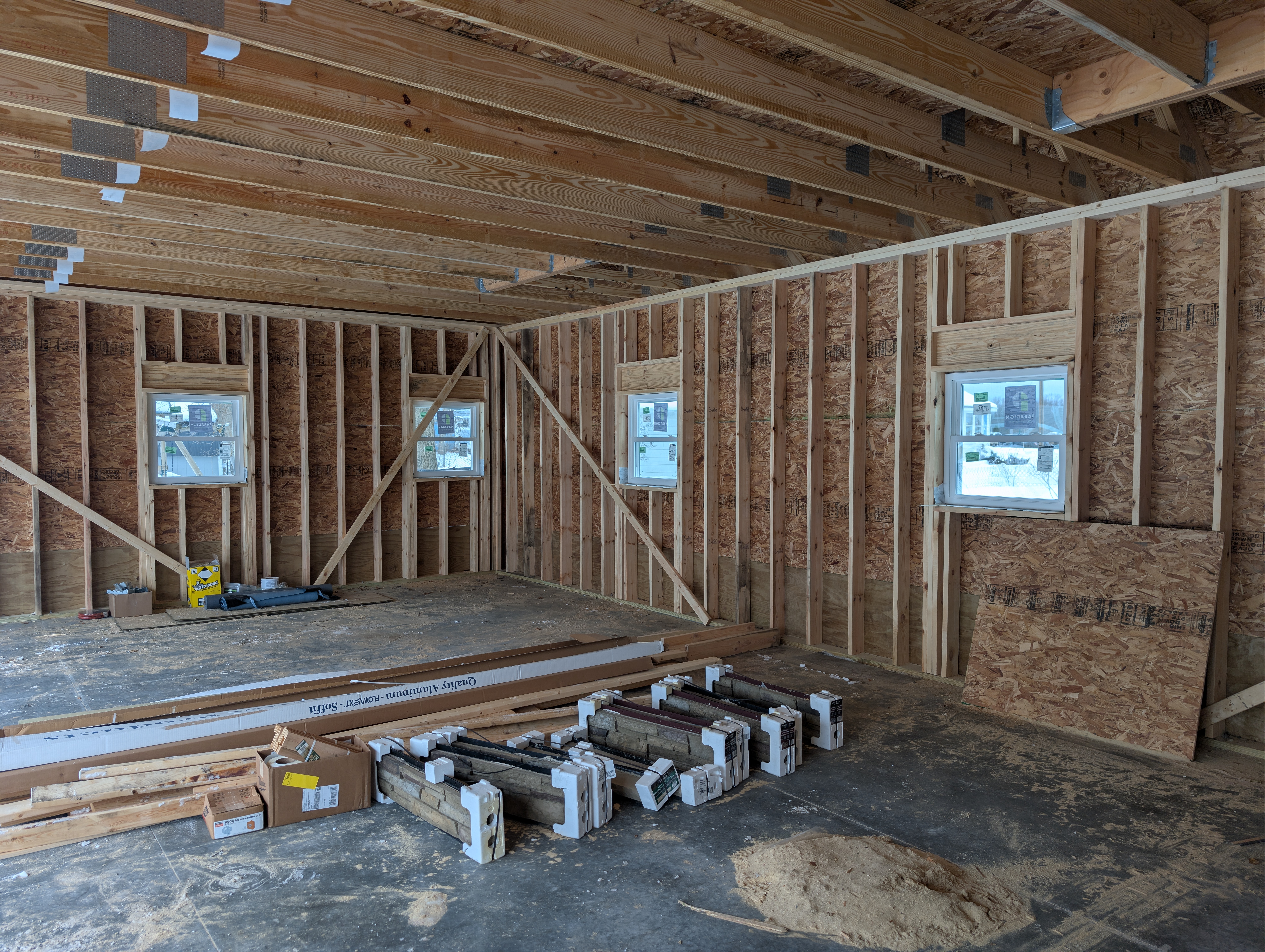 Interior of garage showing framed walls with installed windows and staged materials
