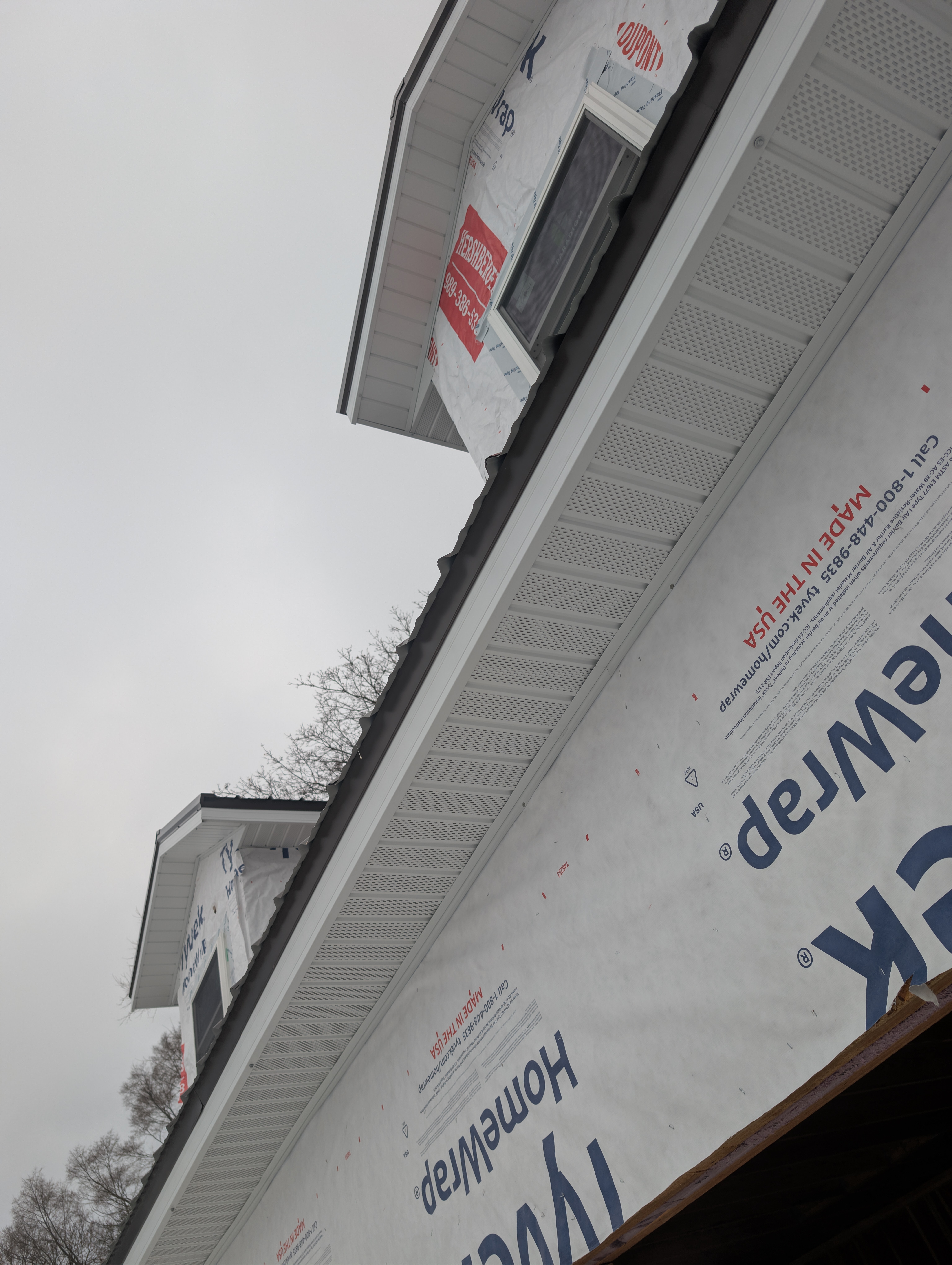 Upward view of vented soffit beneath completed metal roof and dormers