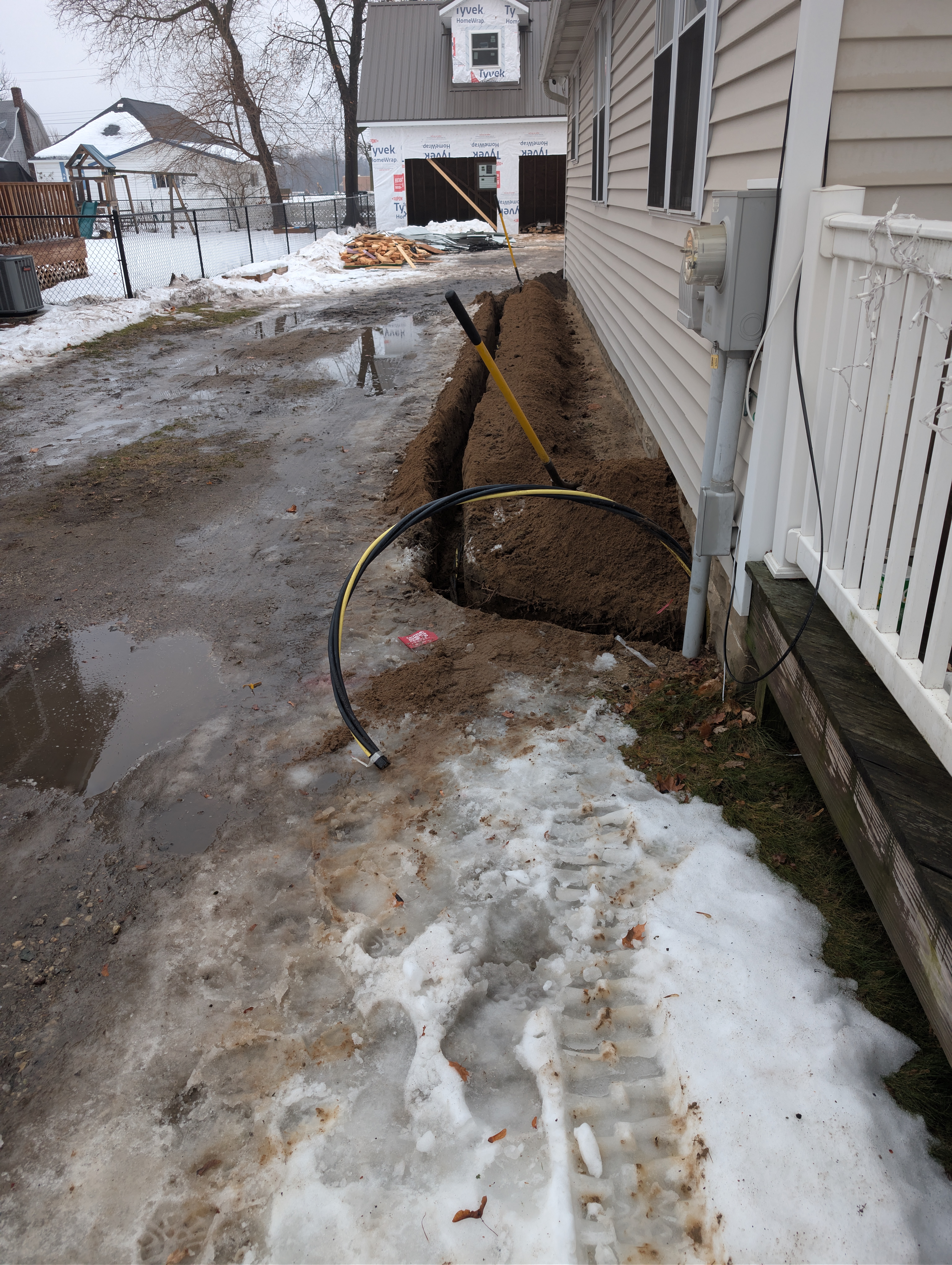 Electrical trench along house side with garage visible in background