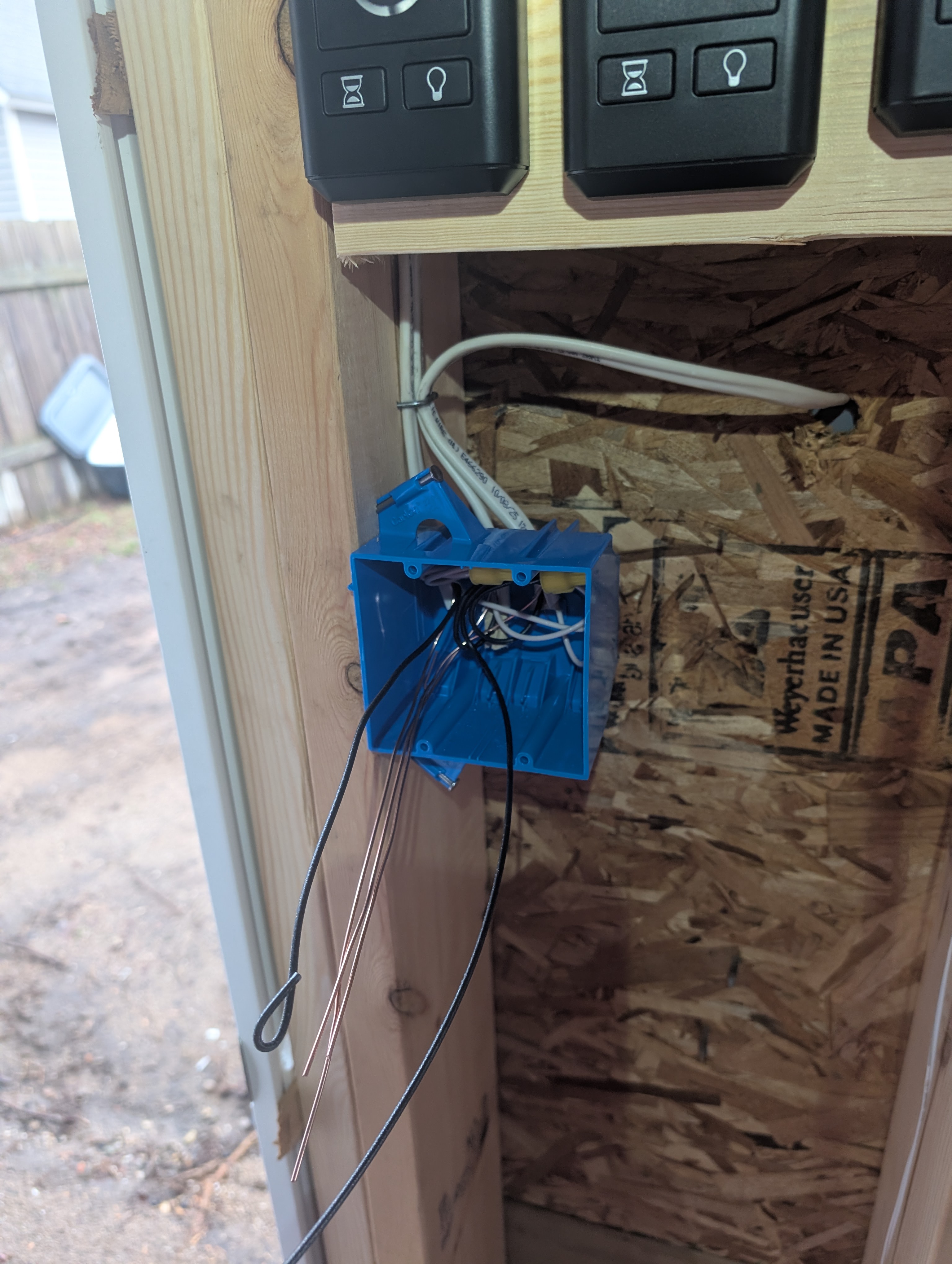 Unfinished single-gang switch box with unterminated wires near garage entry door