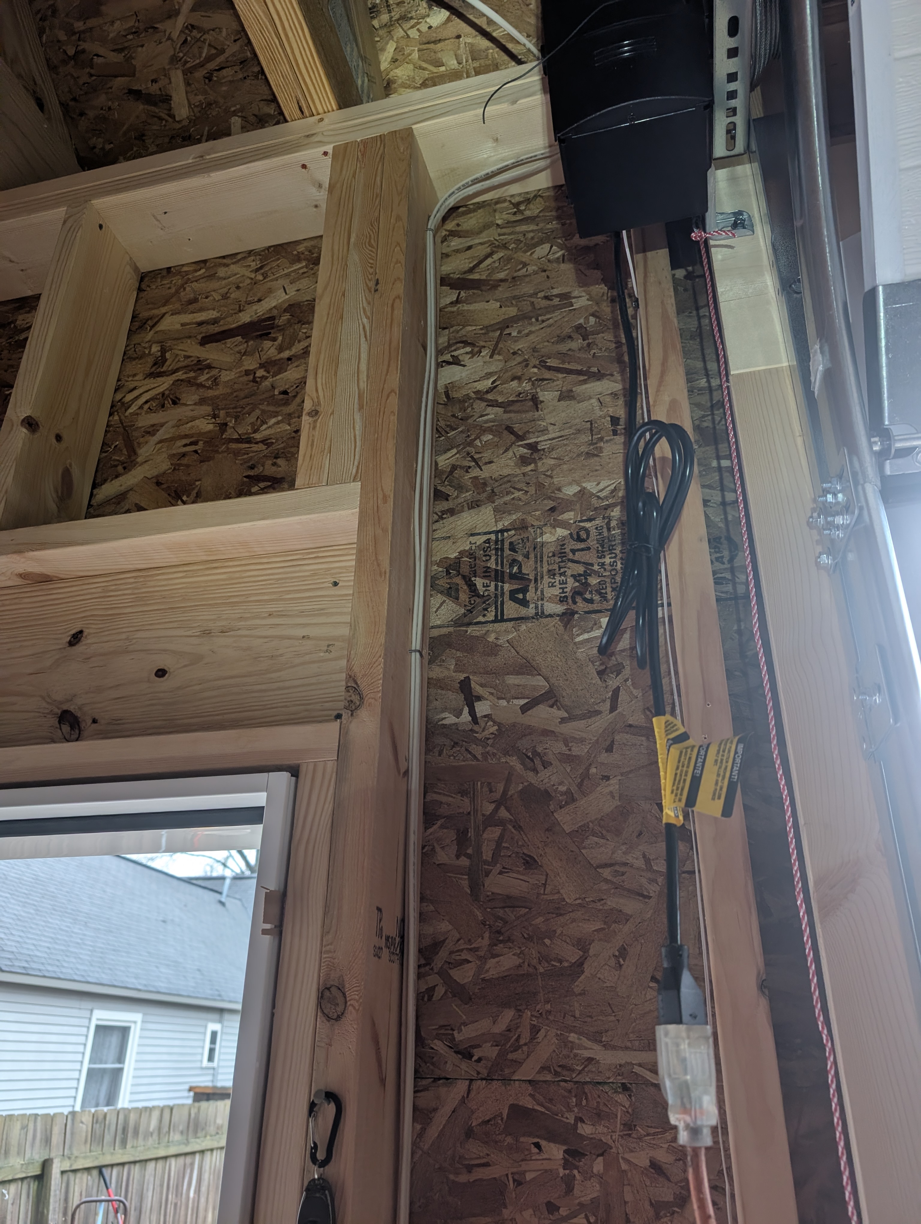 Romex cable routing along wall and ceiling framing near garage entry door