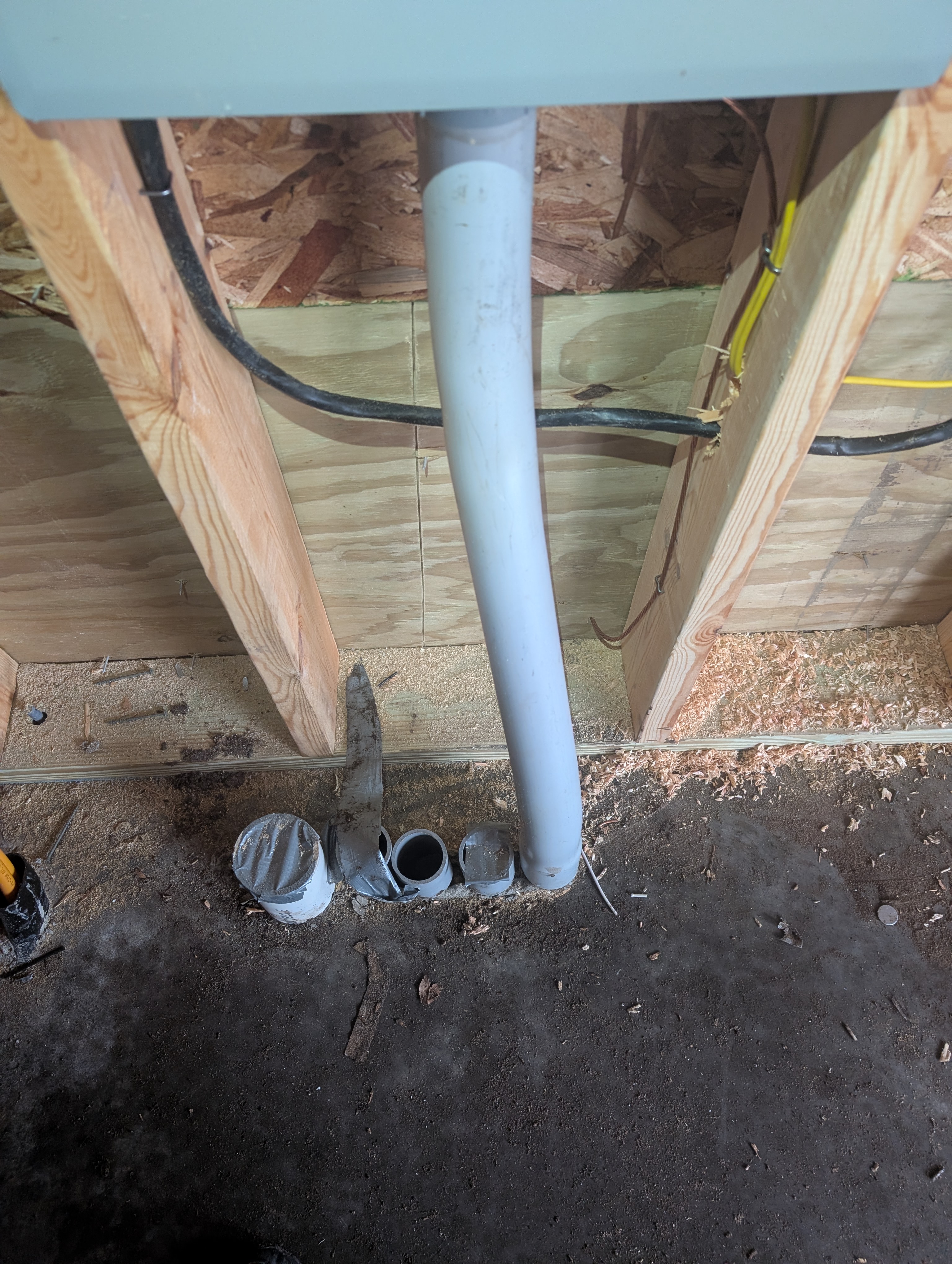 Conduits rising through concrete slab beneath the garage breaker panel