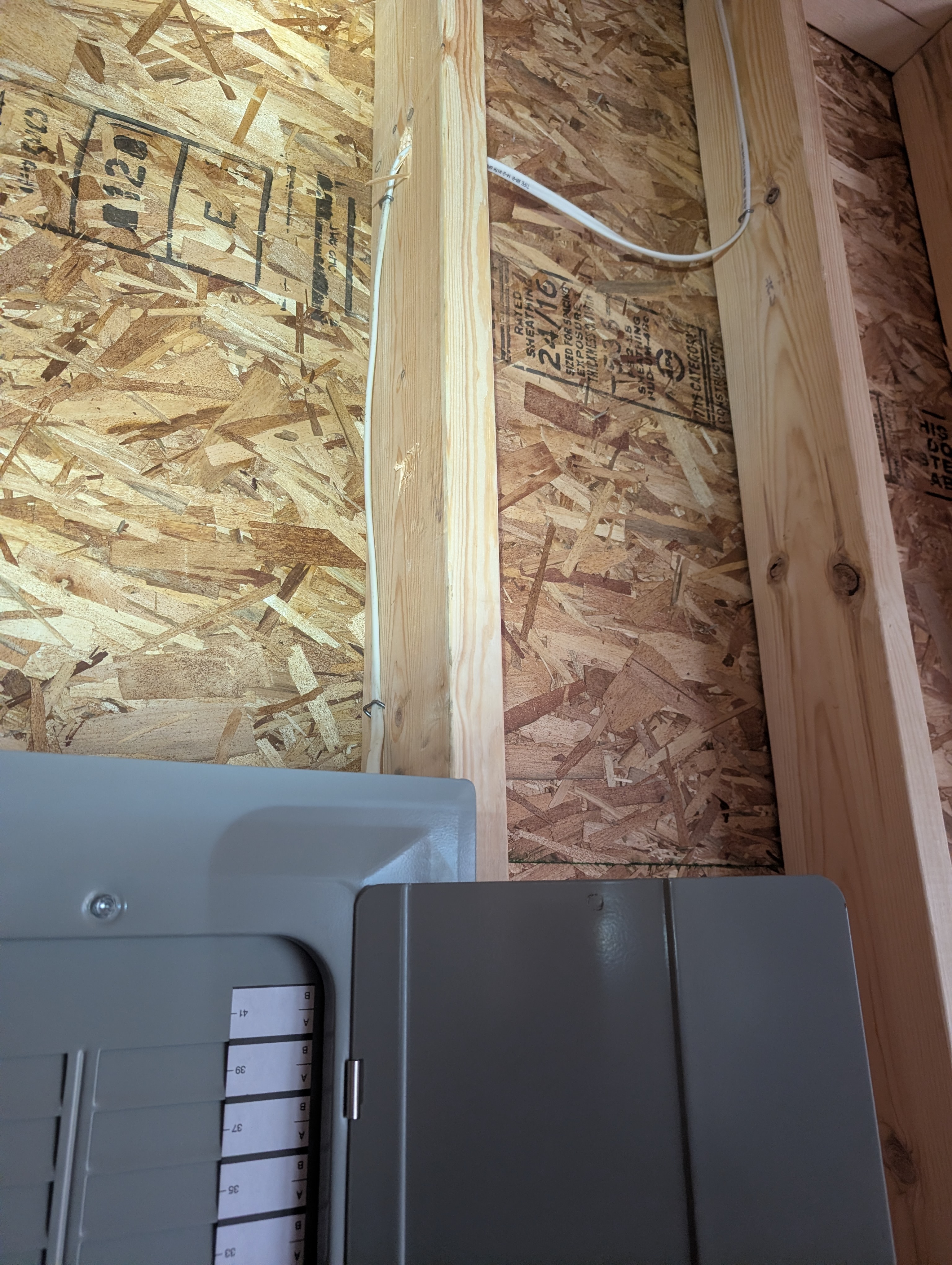 White romex cable routed along OSB wall above the Eaton breaker panel