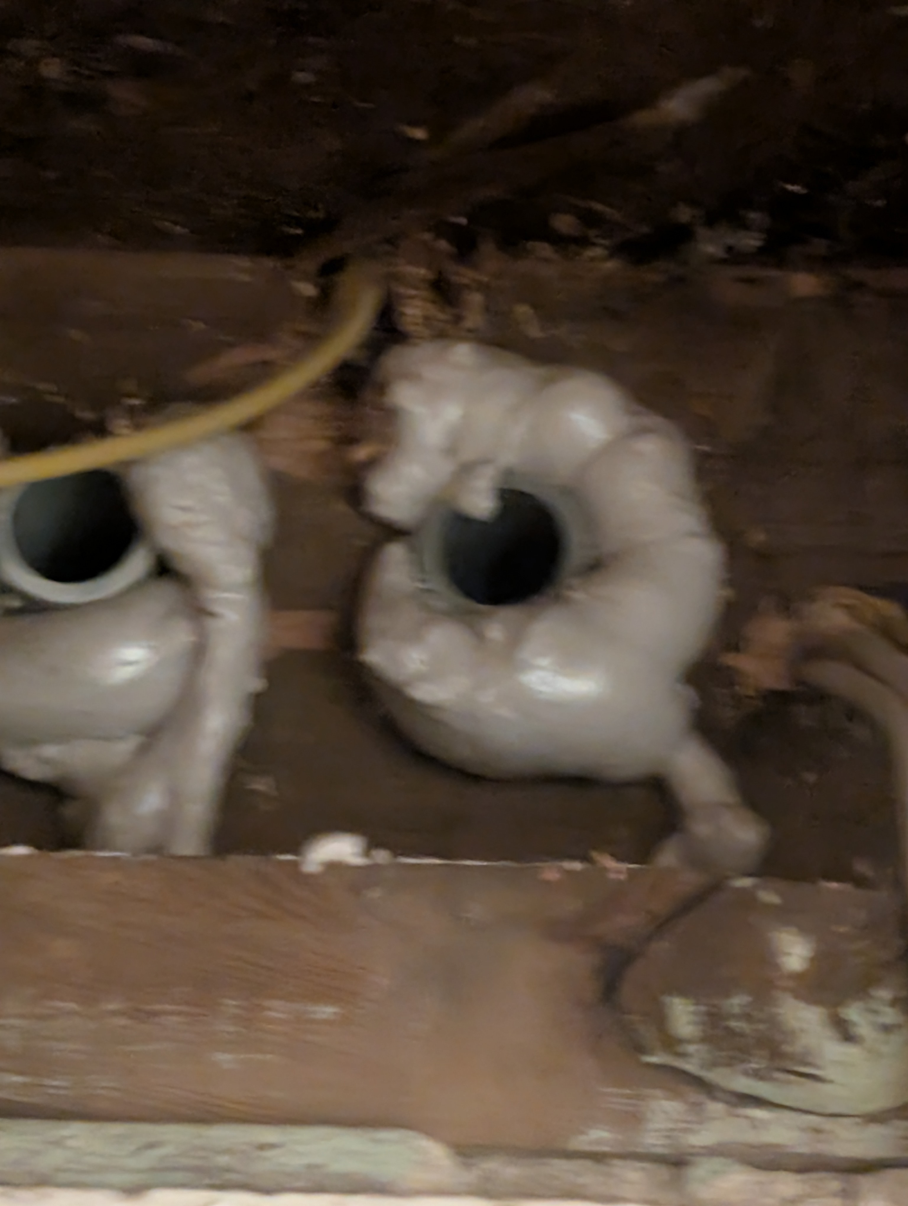 Two 1-inch conduit penetrations through house basement block wall, sealed with expanding foam