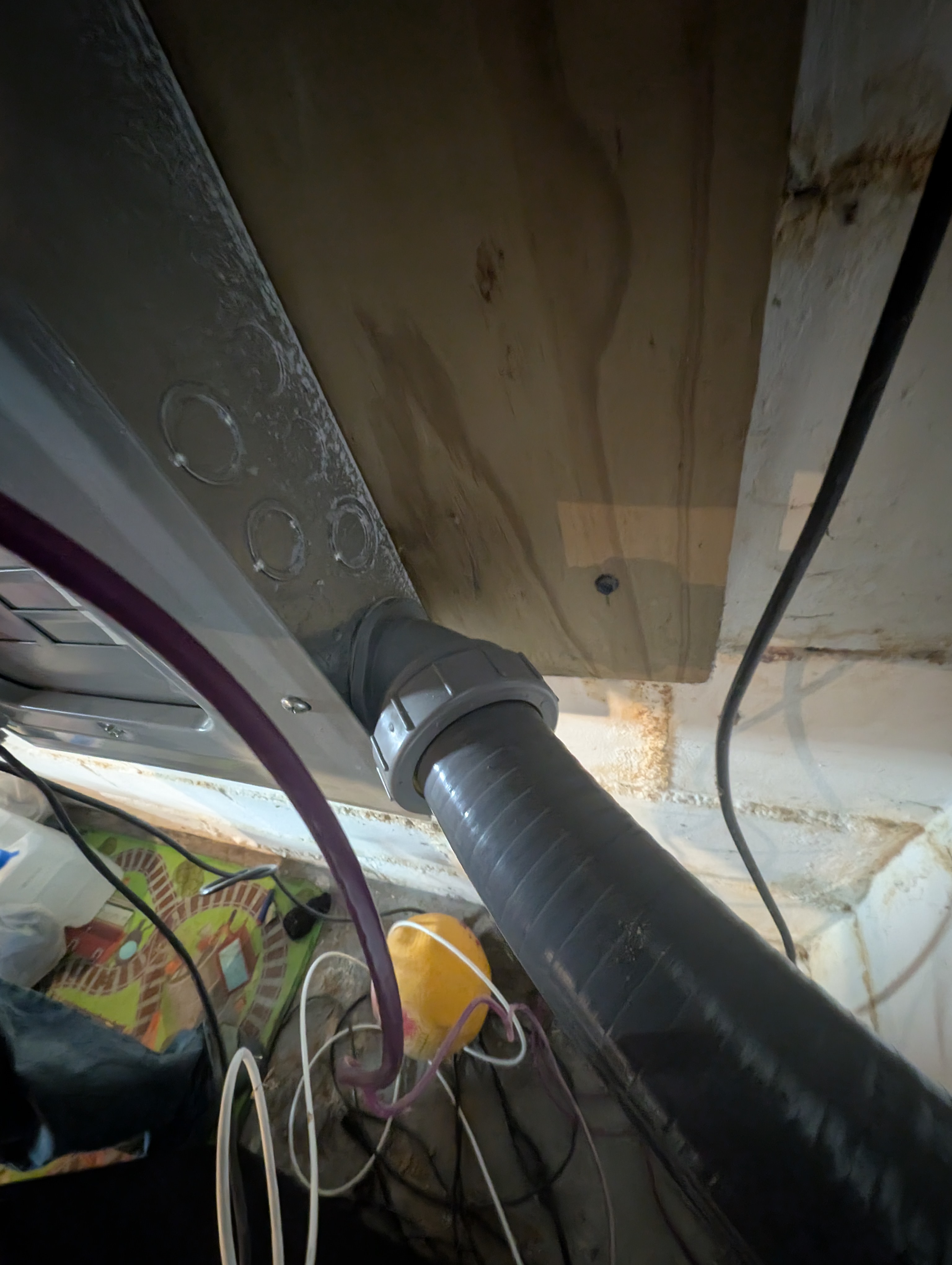 Close-up of black flexible conduit with gray compression connector entering house panel enclosure